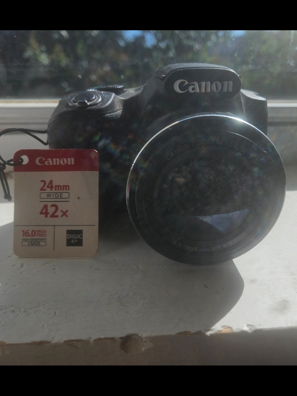 Canon Black Bridge Camera with Prominent Zoom Lens and Red Tag